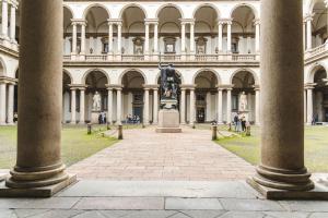 une statue devant un bâtiment avec colonnes dans l'établissement Suite milano brera, à Milan