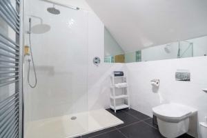 y baño blanco con ducha y aseo. en Trewhiddle Villa 04, en St Austell