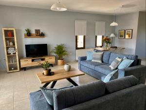 ein Wohnzimmer mit einem blauen Sofa und einem Tisch in der Unterkunft Anemos Apartment in Keramotí