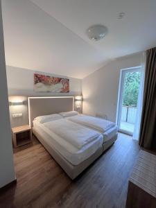 Un dormitorio con una gran cama blanca y una ventana en Apartments Roemerschlucht en Velden am Wörthersee