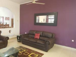 a living room with a brown leather couch and a mirror at Accra Service villas - villa 2? in Spintex