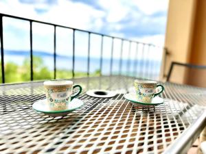 2 tazas de café sentadas en una mesa en un balcón en Casa Giulia: un'oasi di pace, en Toscolano Maderno