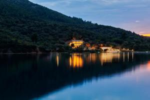 a house on the shore of a lake at night at Chronos Hotel in Porto Koufo