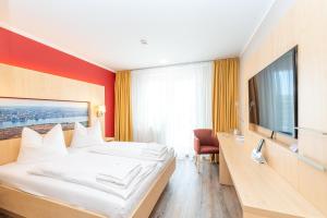 um quarto de hotel com uma cama e uma televisão de ecrã plano em Das Hotel an der Stadthalle - Rostock Hauptbahnhof em Rostock