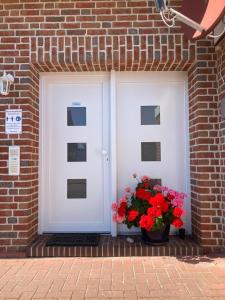 two white doors with flowers in a brick building at Apartment Topp adult only in Wangerland