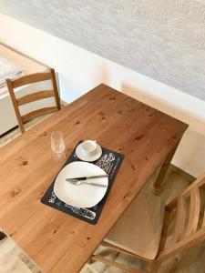 a wooden table with a white plate and fork and knife at Apartment Topp adult only in Wangerland