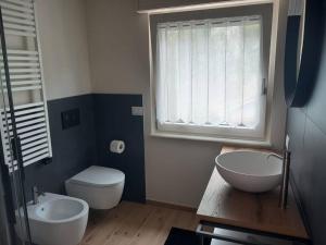 a bathroom with two sinks and a toilet and a window at Casa Maria in Torri del Benaco