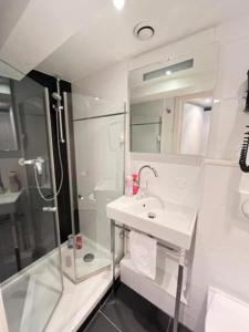 uma casa de banho branca com um lavatório e um chuveiro em Residence OLit Cathédrale em Estrasburgo