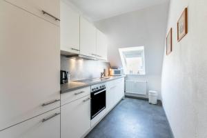 a kitchen with white cabinets and a black oven at Katharina in Westerdeichstrich