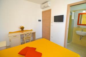 a room with a yellow bed and a sink at B&B Lu Cantoru in Marina di Pescoluse