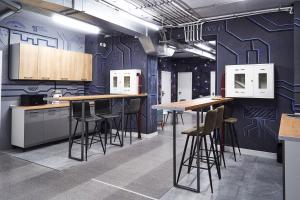 a kitchen with blue walls and bar stools at Gagarin Capsule Hotel in Almaty