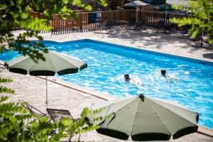 two people swimming in a swimming pool with umbrellas at Huttopia Gorges du Tarn in Les Vignes