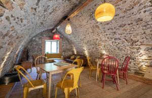 a dining room with tables and chairs and a stone wall at Huttopia Gorges du Tarn in Les Vignes