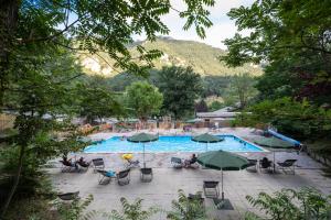 a swimming pool with people sitting in chairs and umbrellas at Huttopia Gorges du Tarn in Les Vignes