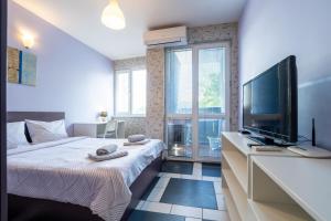 a bedroom with a bed and a flat screen tv at Spacious apartment in the heart of Studentski grad in Sofia