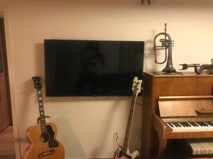 a television on a wall with a guitar and a keyboard at Bolinderbyn in Järfälla