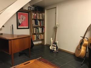 a room with a piano and a guitar and a book shelf at Bolinderbyn in Järfälla