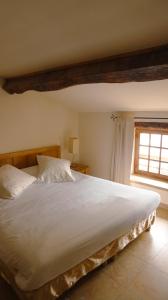 a bedroom with a large white bed with a window at Hôtel la Fête en Provence in Vaison-la-Romaine