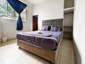 1 dormitorio con 1 cama grande con sábanas moradas en El Mural Backpackers, en Tarapoto