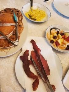 una mesa cubierta con platos de desayuno con tocino en Leslie Manor, en Glasgow