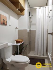 La salle de bains blanche est pourvue d'une douche et de toilettes. dans l'établissement F524 Place at SMDC Cheer Residences by Lee Portum, à Marilao