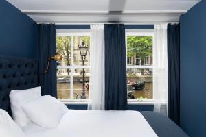 ein Schlafzimmer mit einem Bett und einem großen Fenster in der Unterkunft HEGRA by Stanley Collection in Amsterdam