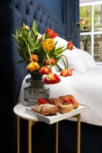 ein Tablett mit Gebäck und Blumen auf einem Tisch neben einem Bett in der Unterkunft HEGRA by Stanley Collection in Amsterdam