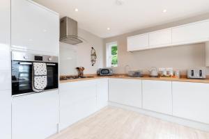 a white kitchen with white cabinets and appliances at Vaughan Lodge- Stunning 2 Bedroom Duplex Apartment in Malvern Wells