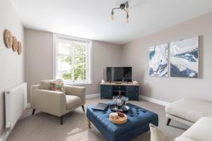 a living room with a blue couch and a tv at Vaughan Lodge- Stunning 2 Bedroom Duplex Apartment in Malvern Wells