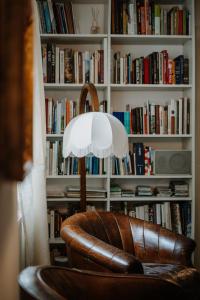 a leather chair with a lamp in front of a book shelf at Ottmanngut Suite and Breakfast in Merano