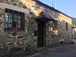 a stone building with a door and a window at Casa Lici in Robles de Laciana