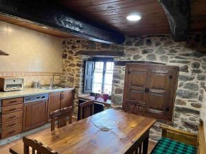 a kitchen with a wooden table and a stone wall at Casa Lici in Robles de Laciana