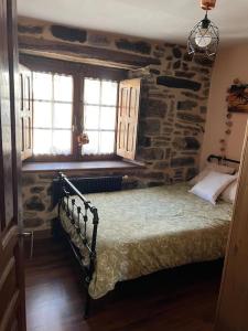 a bedroom with a bed with a stone wall at Casa Lici in Robles de Laciana