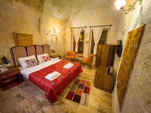 um quarto com uma cama grande e um cobertor vermelho em Heritage Cave Suites em Ürgüp