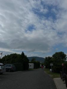 une route avec des voitures garées sur elle et un ciel nuageux dans l'établissement Autocamp Free Star - Mobilheimy, à Strachotín