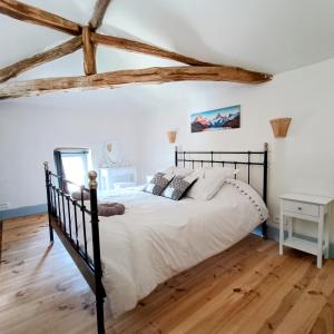 a bedroom with a black bed and wooden floors at Baladous in Montgaillard-de-Salies