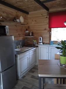 a kitchen with white cabinets and a refrigerator and a table at Chalet Cricri Domaine de la Mamounette in Champclause