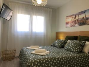 a bedroom with a bed with two towels on it at Apartamento Vicaño - PLAYA SILGAR in Sanxenxo +12 photos