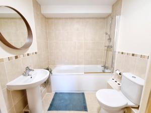 a bathroom with a toilet and a tub and a sink at Cityscape Haven: 1 Bedroom Apartment with Terrace and City view in Bournemouth