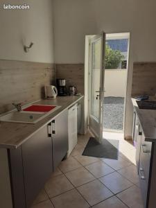 a kitchen with a sink and a door to a patio at La Ferme de Barville & SPA in Écrammeville