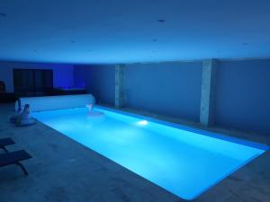 a swimming pool with blue lights in a room at La Ferme de Barville & SPA in Écrammeville