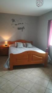 a bedroom with a wooden bed with words on the wall at La Ferme de Barville & SPA in Écrammeville
