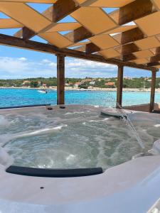 a jacuzzi tub with a wooden ceiling and water at Luxury villa Vela Rina in Mali Drvenik