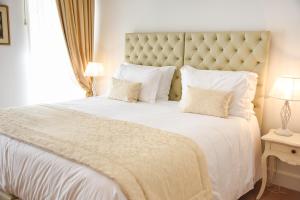 a bedroom with a large bed with white sheets and pillows at Sra da Oliveira Solar Heritage in Leiria +37 photos