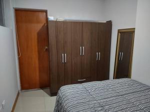 a bedroom with a bed and wooden cabinets at Hospedaje Libertador San Martín - Dpto. entero # 1 in Víctor Larco Herrera