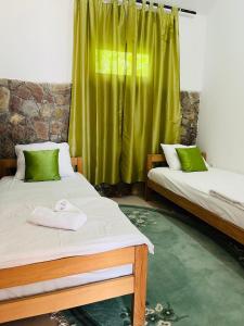 duas camas num quarto com uma cortina verde em Apartment with river Una view / Ilma 2 em Bihać
