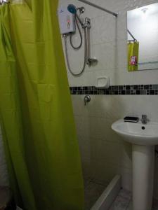 a bathroom with a green shower curtain and a sink at Hospedaje Libertador San Martín - Dpto. entero # 1 in Víctor Larco Herrera