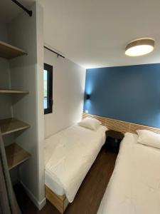 two beds in a room with a blue wall at L'Ecrin d'Edern 4pers Mont Dore in Le Mont-Dore