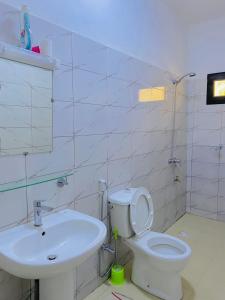 a white bathroom with a toilet and a sink at Appartement xandra in Dakar