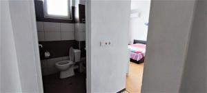 a bathroom with a toilet and a room with a bed at Къща за гости "Венито" in Sinemorets